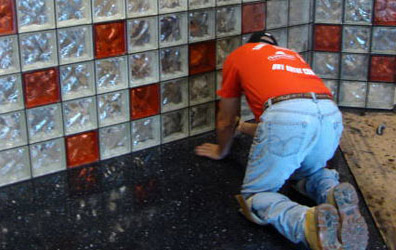 black grout being applied to a glass block counter wall 