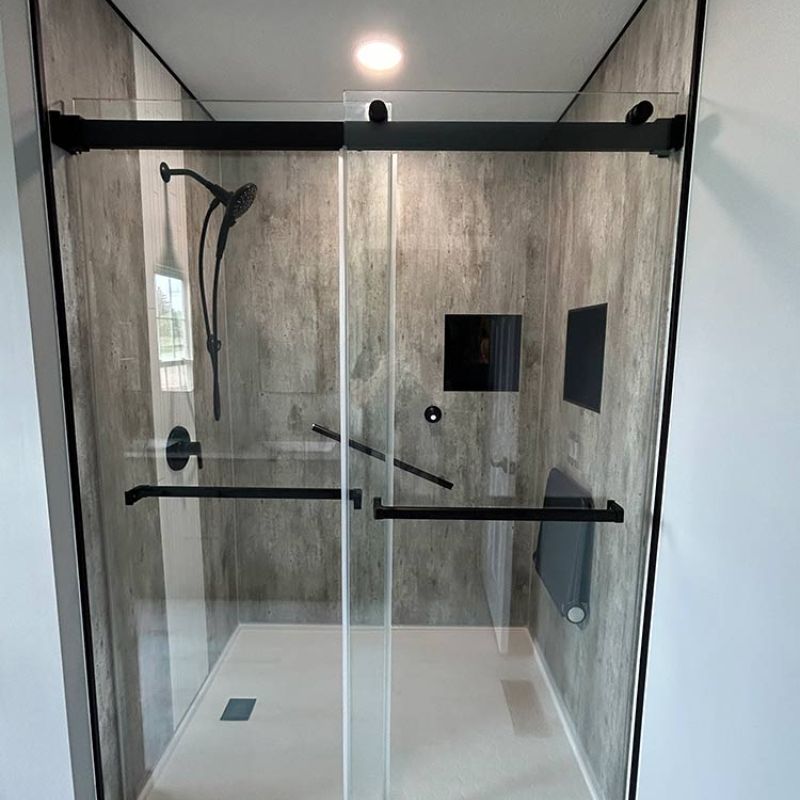 AFTER - new shower base, bypass glass doors, black trim, concrete laminate wall panels