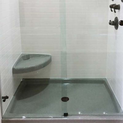 Curved corner seat in a solid surface shower with a pivoting shower door - Innovate Building Solutions 
