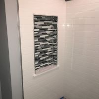 Close up of a tile niche surrounded by white subway pattern solid surface walls 