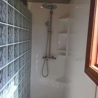 Glass block walk in shower with white high gloss solid surface wall panels and a triple corner caddy 