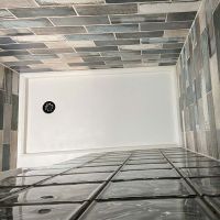 Top down view of white solid surface shower pan with a wave glass block wall - Innovate Building Solutions 