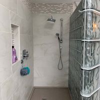 Solid surface shower pan with a custom drain location in a glass block shower project - Innovate Building Solutions 