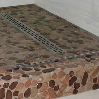 Linear drain in a river rock covered ready for tile shower pan - Innovate Building Solutions 