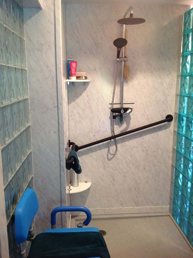 Marble pattern PVC composite wall panels in a light blue glass block shower - Innovate Building Solutions 