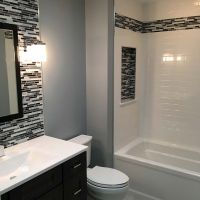 White subway tile solid surface tub wall panels with an acrylic tub and tile niche in Parma Heights  by The Bath Doctor 