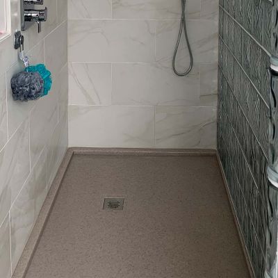 Square drain in a cultured granite shower pan in a gray color - Innovate Building Solutions 