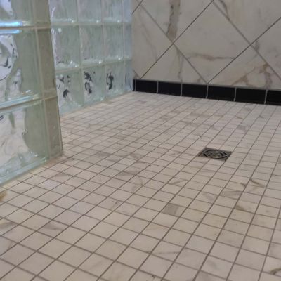 Square tile drain in a one level glass block shower with mosaic tiles - Innovate Building Solutions 