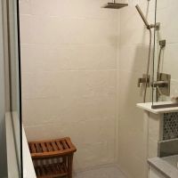 Stone tile cultured granite shower walls with a custom glass dividers for a walk in shower 