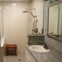 Cultured granite stone tile pattern shower wall panels with a pony wall and solid surface pan 