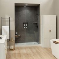 Modern bathroom featuring Graphite Marble slab-look shower wall panels, a frameless glass shower enclosure, white shaker cabinetry with gold hardware, light wood flooring, a built-in shower bench, and a freestanding soaking tub.