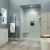Coastal-inspired bathroom featuring Arctic Vein marble-look shower wall panels, soft blue walls, a white shaker vanity with gold hardware, light gray wood-look flooring, a frameless glass shower, and a freestanding soaking tub.