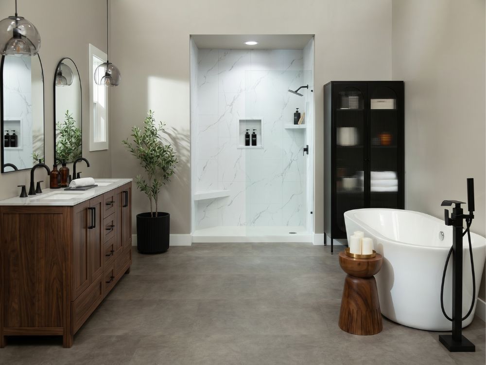 Modern bathroom featuring White Carrara marble-look shower wall panels in an 18x32 vertical staggered pattern, walnut vanity cabinets, matte black fixtures, a freestanding soaking tub, gray floor tile, and a spacious walk-in shower with built-in niches