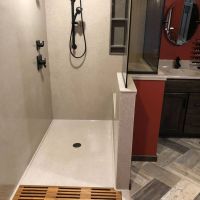 Custom sized solid surface shower pan with a custom teak floor in lay 