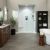 Modern bathroom featuring White Carrara marble-look shower wall panels in an 18x32 vertical staggered pattern, walnut vanity cabinets, matte black fixtures, a freestanding soaking tub, gray floor tile, and a spacious walk-in shower with built-in niches