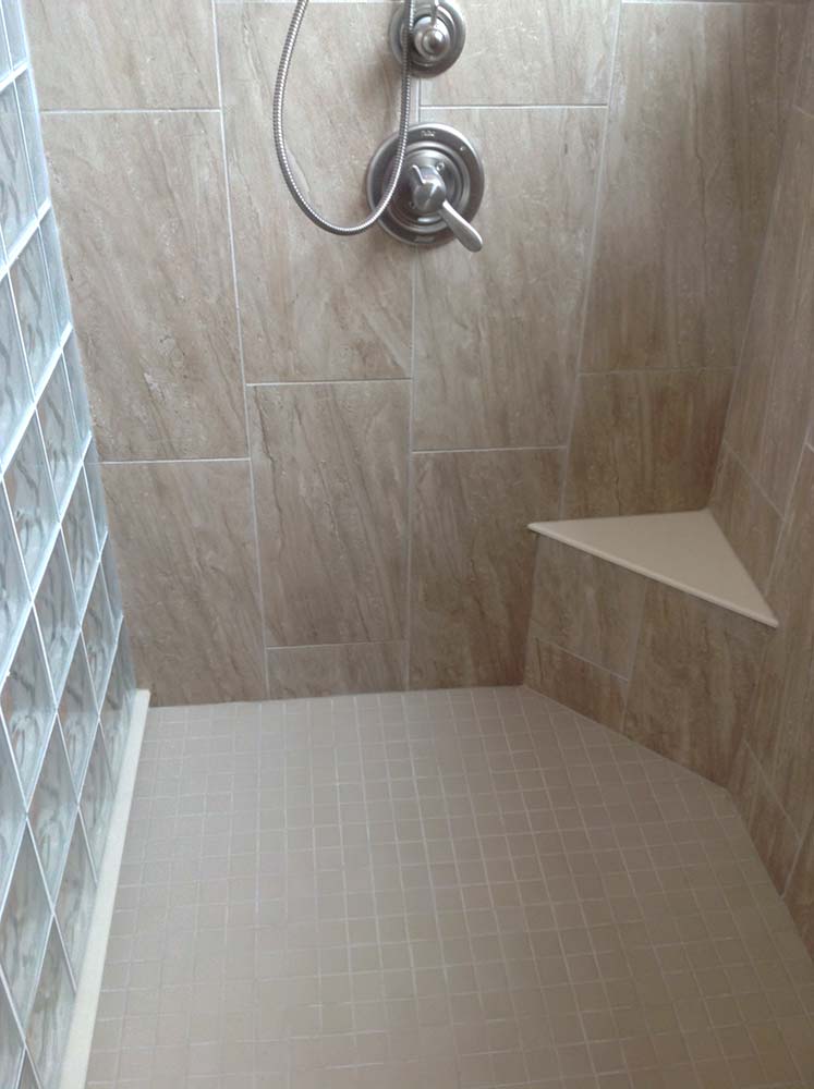 Corner seat in a glass block shower with a solid surface top