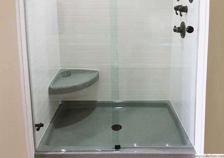 Curved corner seat in a solid surface shower with a pivoting shower door - Innovate Building Solutions 
