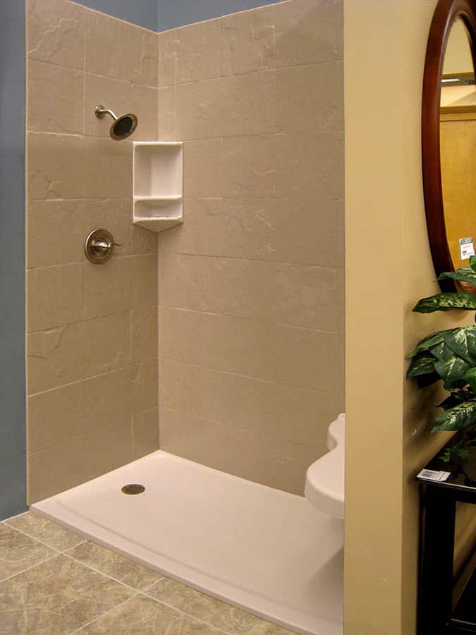 Stone tile pattern solid surface wall with a low profile shower pan and curved extended bench seat 
