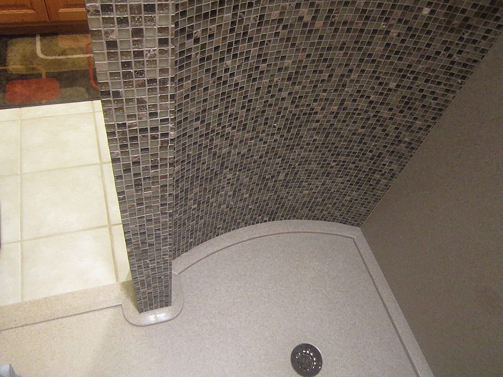 Walk in shower with a curved custom shower pan around a framed curved wall