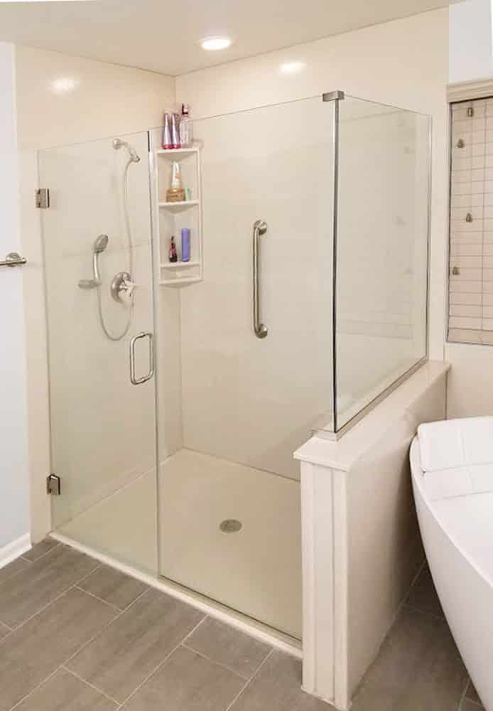Low profile cultured granite shower pan walls with a triple corner caddy and custom pivoting glass door 